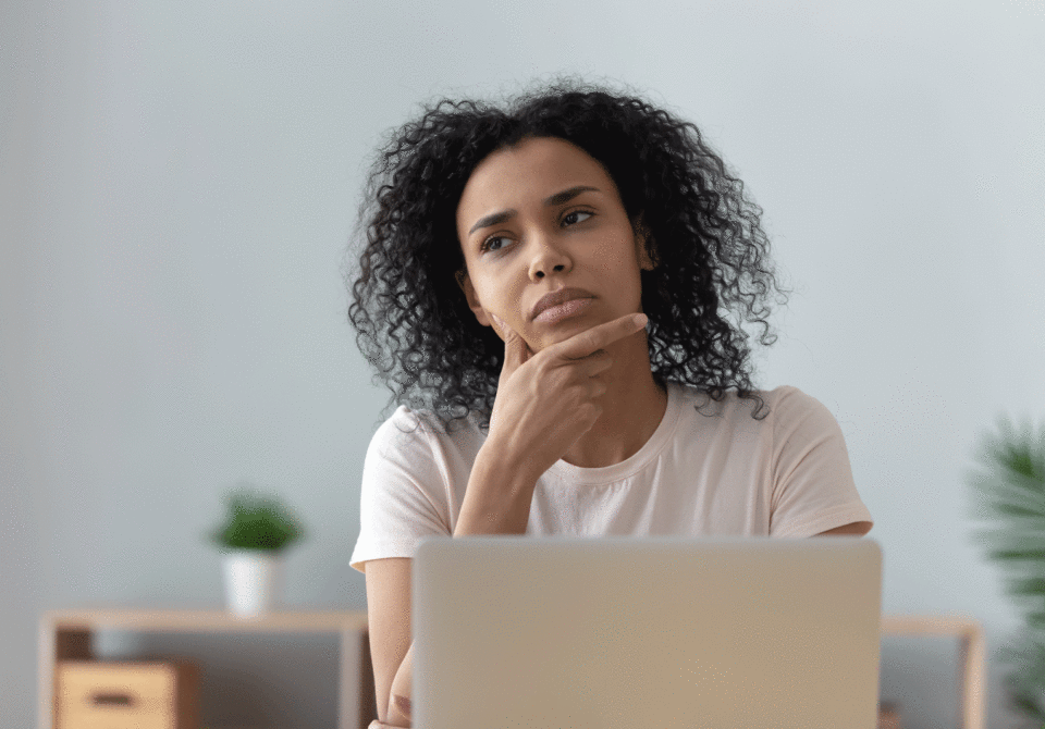 A woman at her computing looking pensive