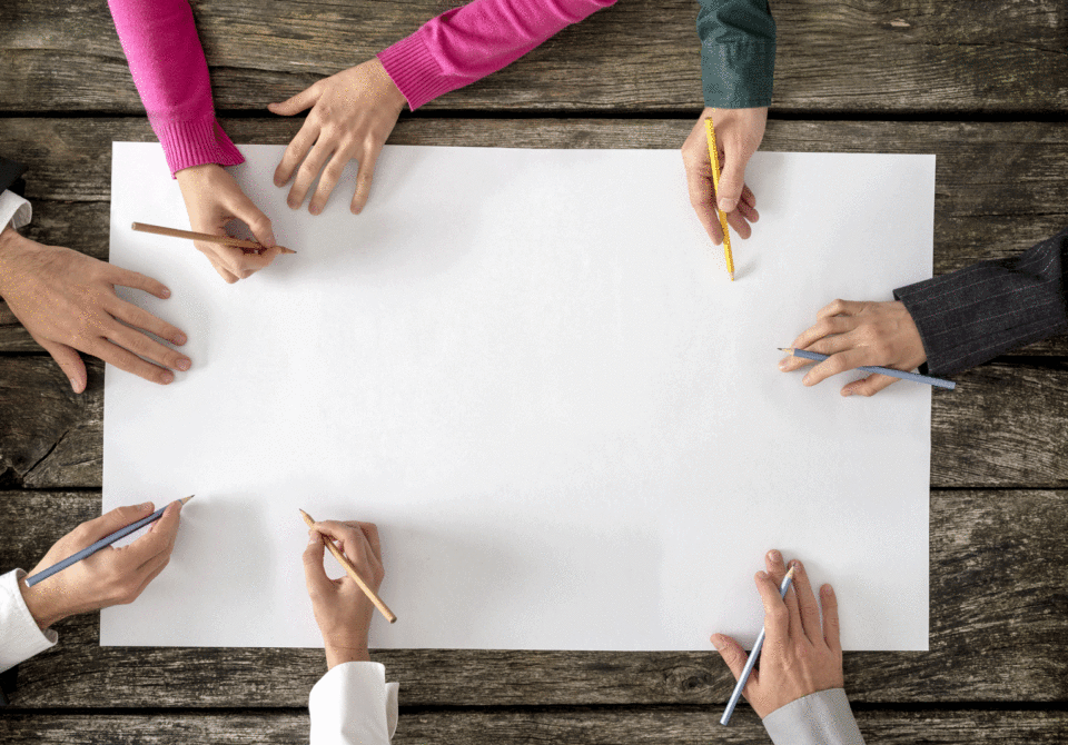 A bunhc of hands working together to sketch on a piece of paper